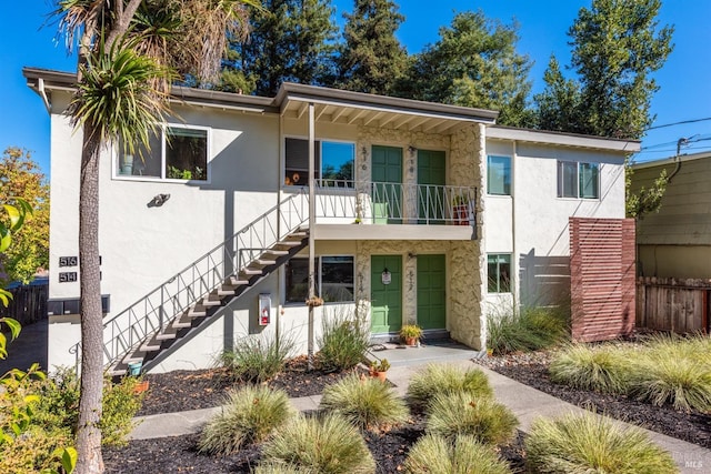 view of front of house with stairway, fence, and stucco siding