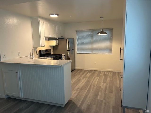 kitchen with a peninsula, wood finished floors, gas stove, and a sink