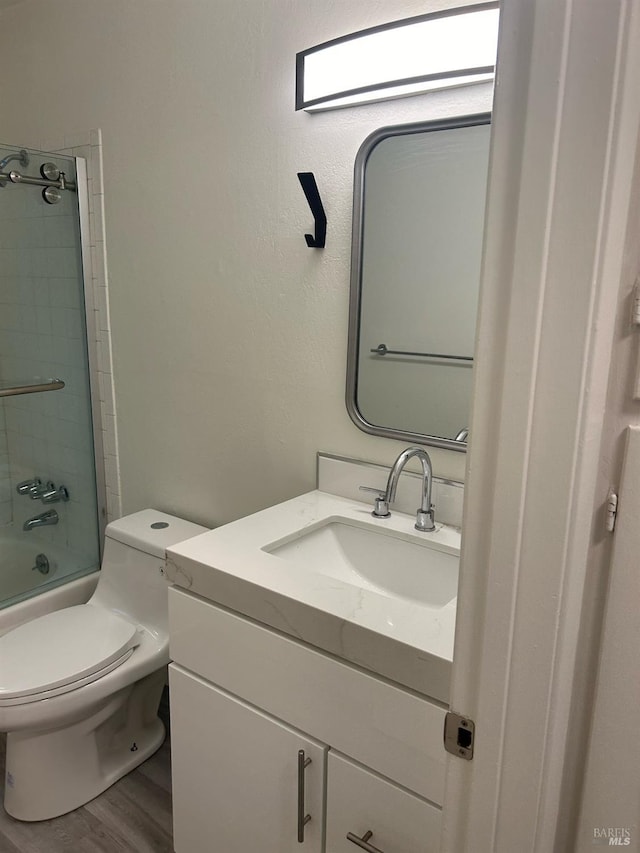 full bathroom with tiled shower / bath, vanity, wood-type flooring, and toilet