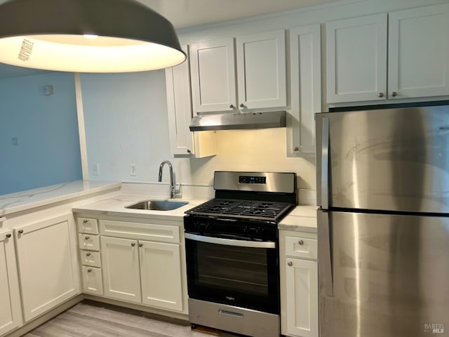 kitchen featuring light stone counters, stainless steel appliances, a sink, light wood-type flooring, and under cabinet range hood