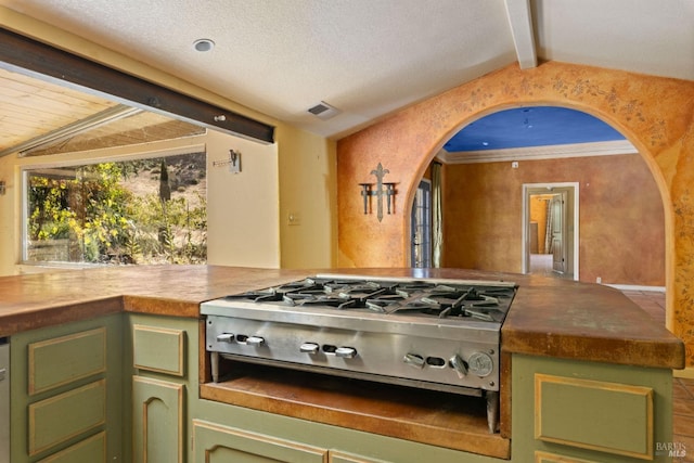 kitchen featuring stainless steel gas stovetop, crown molding, vaulted ceiling with beams, and green cabinets