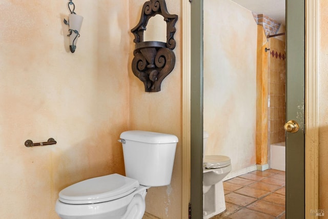 bathroom with toilet, tiled shower / bath, and tile patterned floors