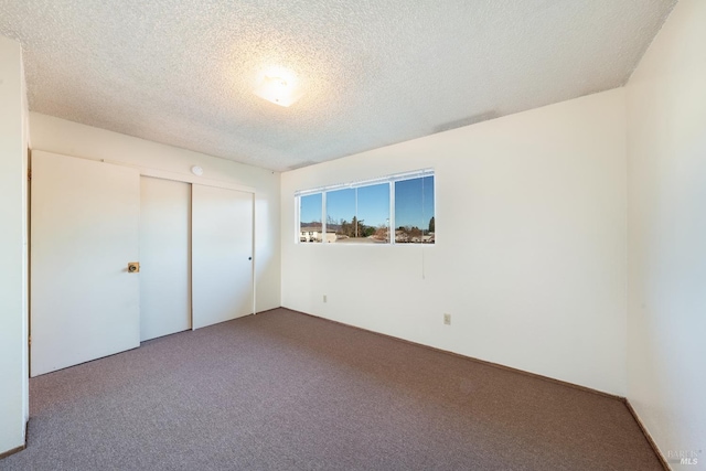 unfurnished bedroom featuring a textured ceiling, carpet floors, and a closet