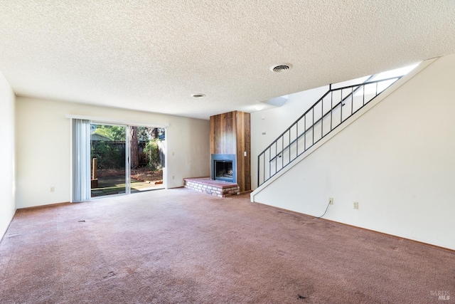 unfurnished living room with carpet, a large fireplace, and a textured ceiling