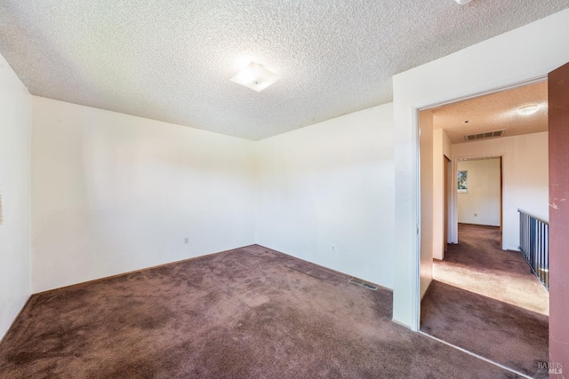 empty room with dark carpet and a textured ceiling