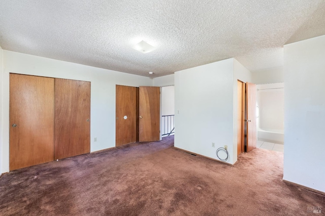 unfurnished bedroom with connected bathroom, dark carpet, and a textured ceiling