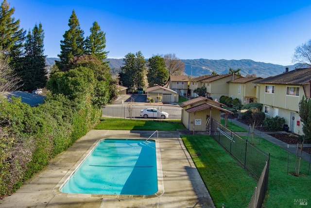 view of pool with a mountain view and a yard