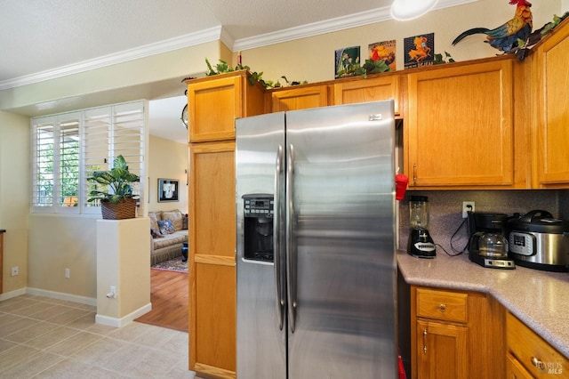 kitchen featuring backsplash, light tile patterned flooring, crown molding, and stainless steel refrigerator with ice dispenser