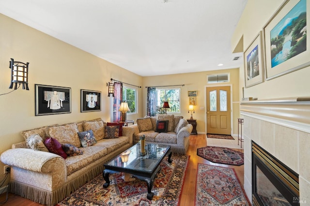 living room with a tiled fireplace and light wood-type flooring