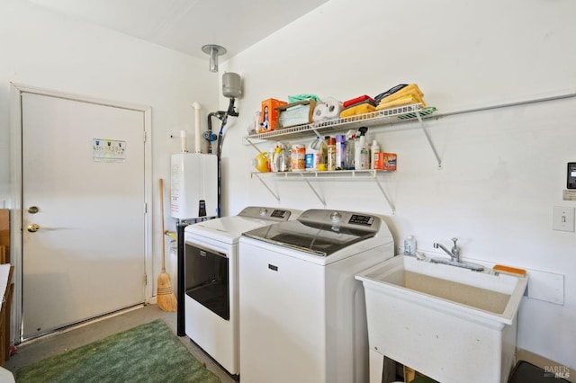 clothes washing area with washing machine and dryer, water heater, and sink