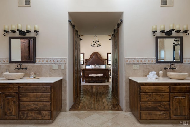 ensuite bathroom with connected bathroom, visible vents, and a sink