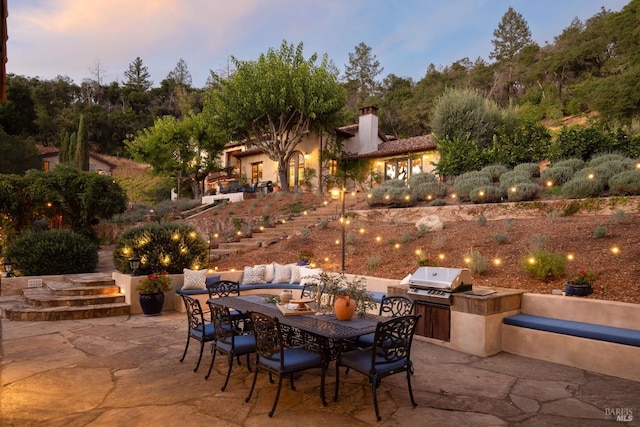 view of patio with outdoor dining area, an outdoor kitchen, stairway, and area for grilling