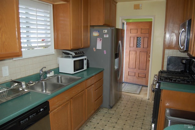 kitchen featuring gas stove, backsplash, dishwashing machine, and sink