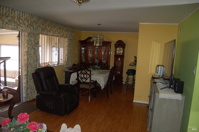 dining area with hardwood / wood-style flooring, ornamental molding, and an inviting chandelier