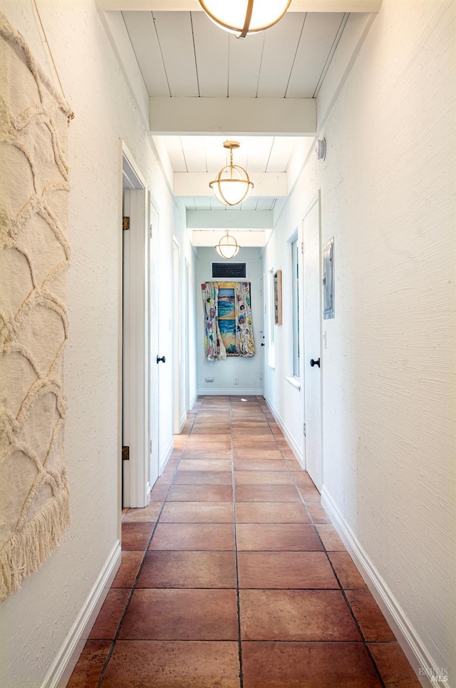 corridor with beamed ceiling, baseboards, and a textured wall