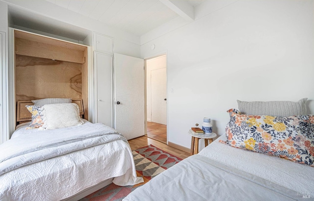 bedroom featuring beamed ceiling and wood-type flooring