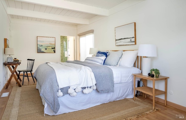 bedroom featuring beam ceiling, wood finished floors, and baseboards