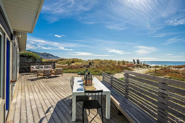 wooden terrace with an outdoor living space, a beach view, and a water view