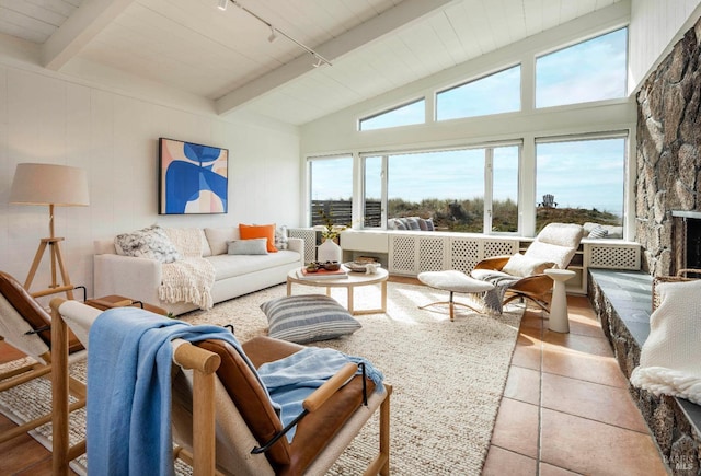 living room with a wealth of natural light, light tile patterned floors, track lighting, and lofted ceiling with beams