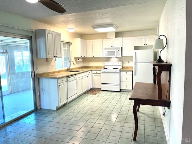 kitchen with white appliances, white cabinets, a textured ceiling, and sink