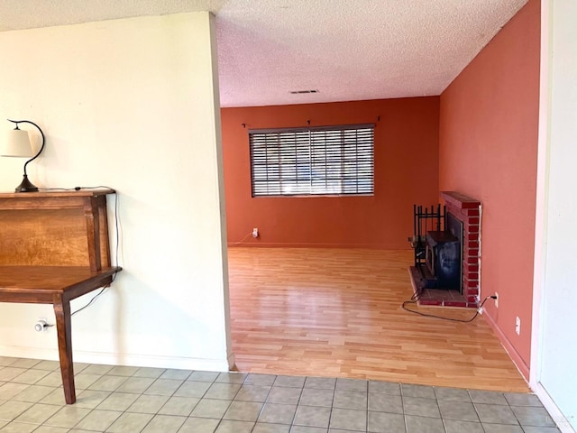 unfurnished living room featuring a textured ceiling, light hardwood / wood-style floors, and a wood stove