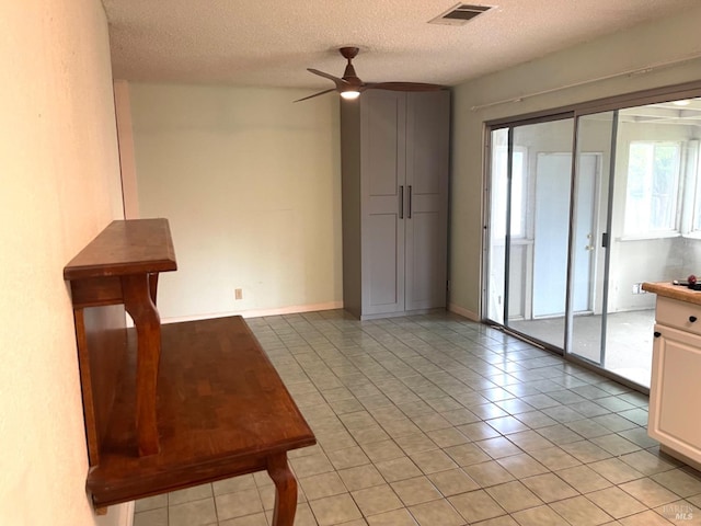 spare room with ceiling fan, light tile patterned flooring, and a textured ceiling