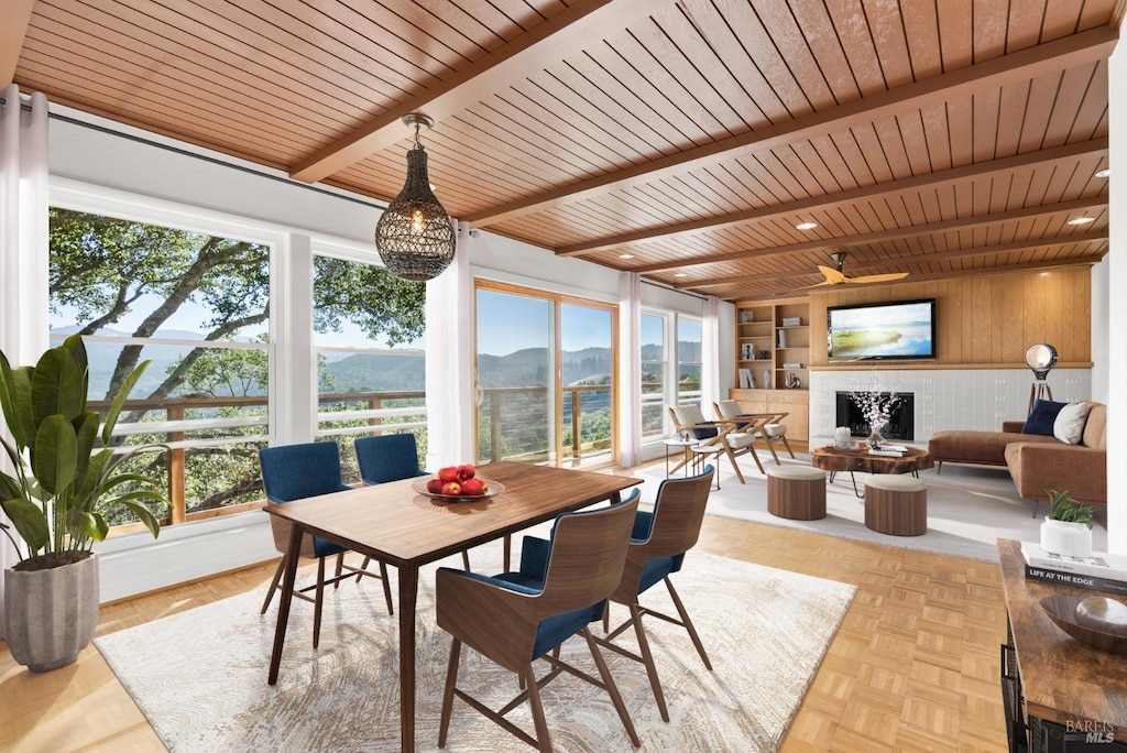 sunroom with ceiling fan, beamed ceiling, wood ceiling, and a brick fireplace