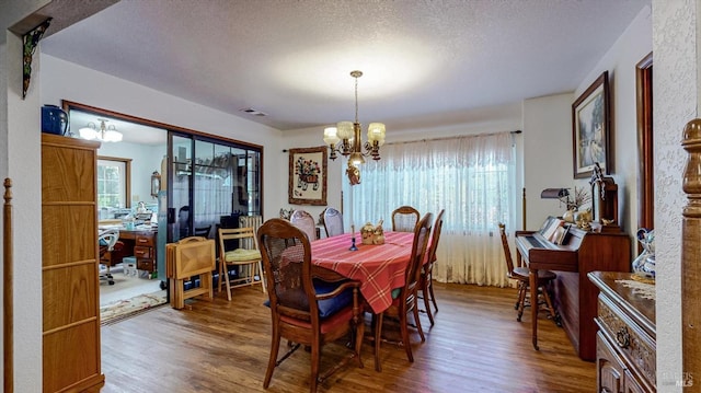 dining space featuring a textured ceiling, a chandelier, and dark wood-type flooring