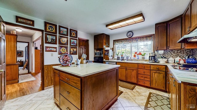 kitchen featuring appliances with stainless steel finishes, sink, backsplash, a center island, and light hardwood / wood-style flooring