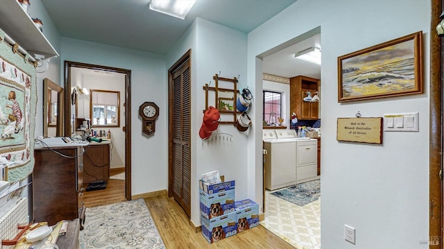 hallway featuring light hardwood / wood-style floors, washer and clothes dryer, and a wealth of natural light