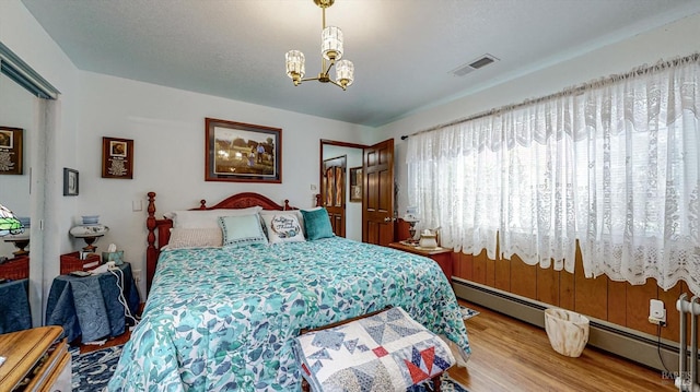 bedroom featuring a notable chandelier, a baseboard radiator, and hardwood / wood-style floors