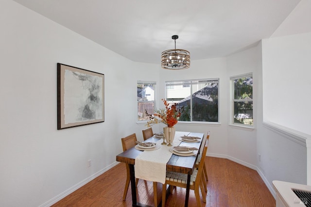 dining area with baseboards, a chandelier, and wood finished floors