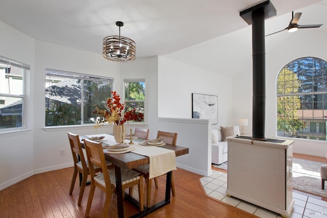 dining space featuring a wood stove, light wood finished floors, baseboards, and a wealth of natural light