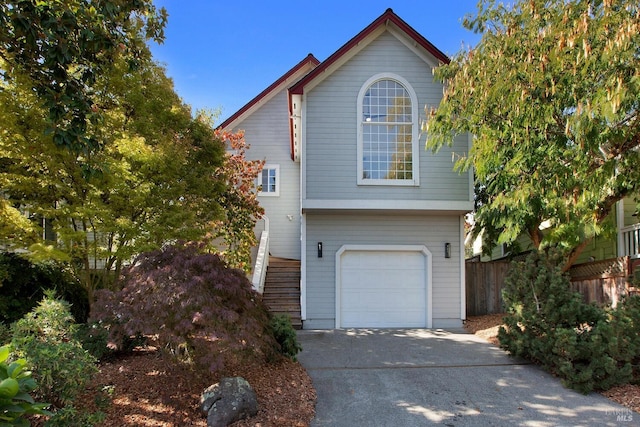 view of front of home with stairs, driveway, fence, and a garage