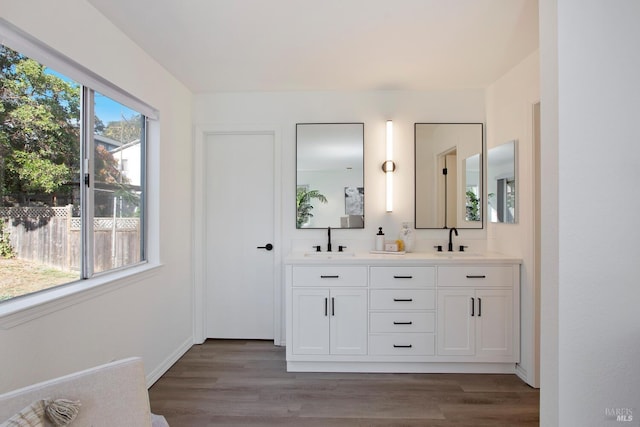 bathroom with double vanity, a sink, and wood finished floors