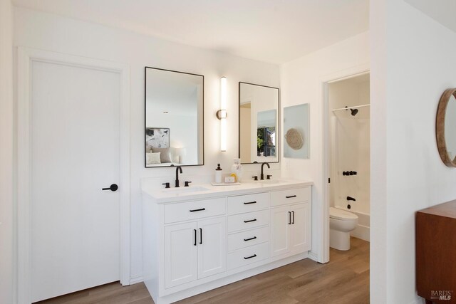 bathroom featuring wood finished floors, a sink, and double vanity