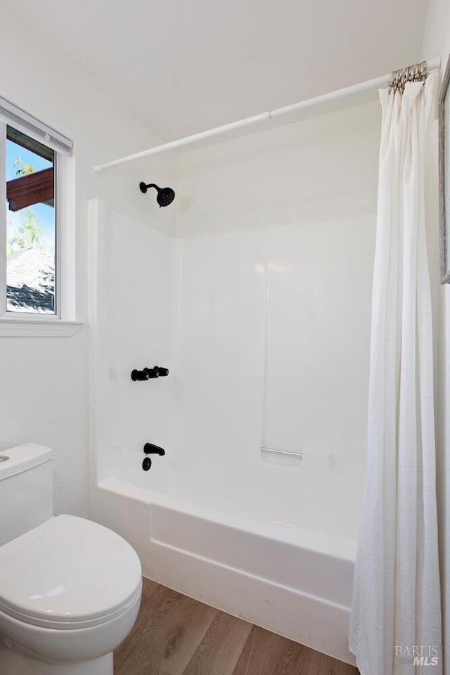 full bath featuring shower / bath combo with shower curtain, toilet, and wood finished floors