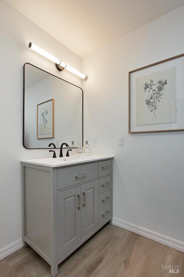 bathroom featuring baseboards, wood finished floors, and vanity