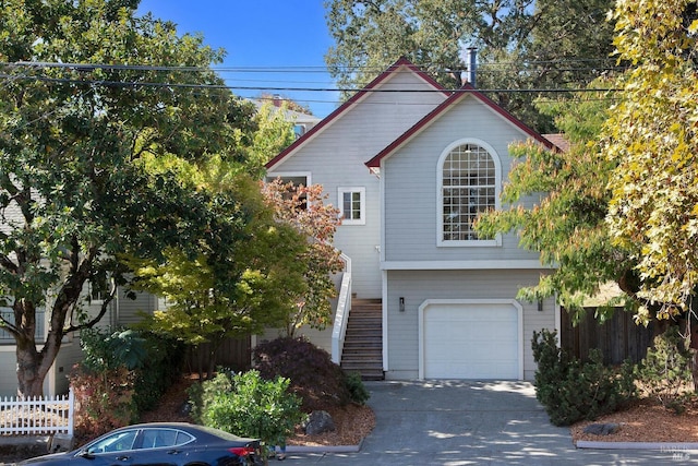 view of front of house featuring stairs, driveway, an attached garage, and fence