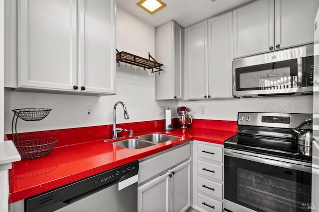 kitchen with appliances with stainless steel finishes, white cabinetry, and sink