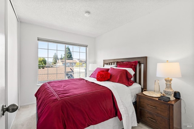 bedroom with light carpet and a textured ceiling