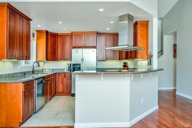 kitchen with sink, dark stone counters, wall chimney range hood, and light wood-type flooring