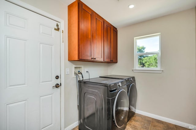 washroom featuring cabinets, dark tile patterned flooring, and washer and dryer