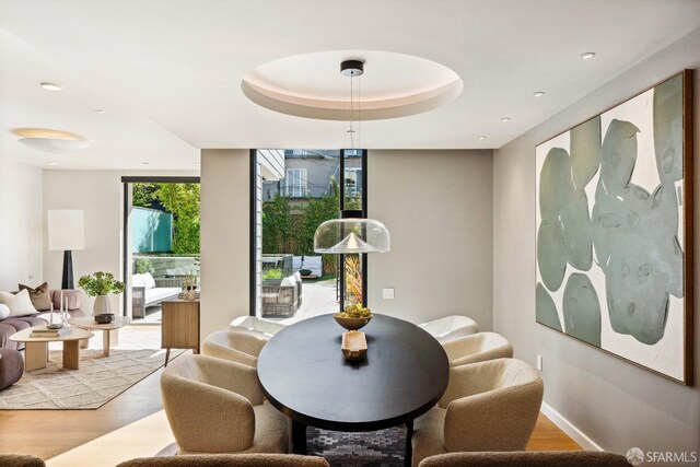 dining room with expansive windows, a tray ceiling, and light hardwood / wood-style floors