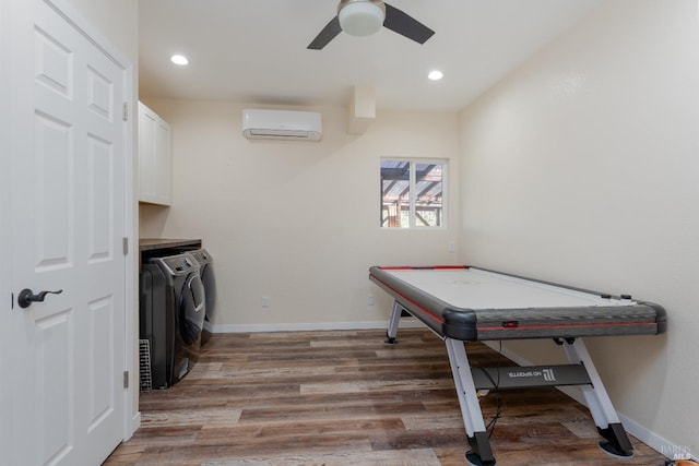 recreation room with hardwood / wood-style flooring, ceiling fan, separate washer and dryer, and a wall unit AC