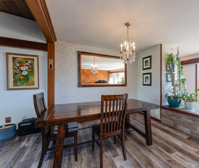 dining area with hardwood / wood-style floors, a textured ceiling, and an inviting chandelier