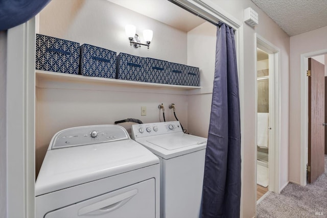 laundry room with a textured ceiling, washer and clothes dryer, and light colored carpet