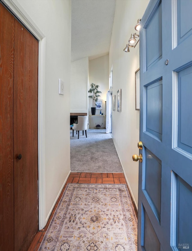 hallway featuring lofted ceiling and dark colored carpet