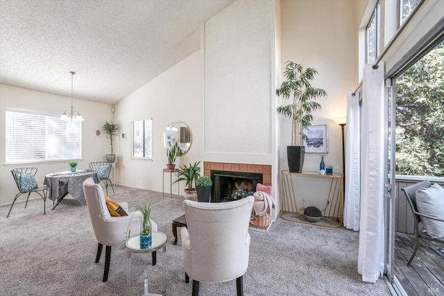 dining space featuring light carpet, a textured ceiling, high vaulted ceiling, and a tile fireplace