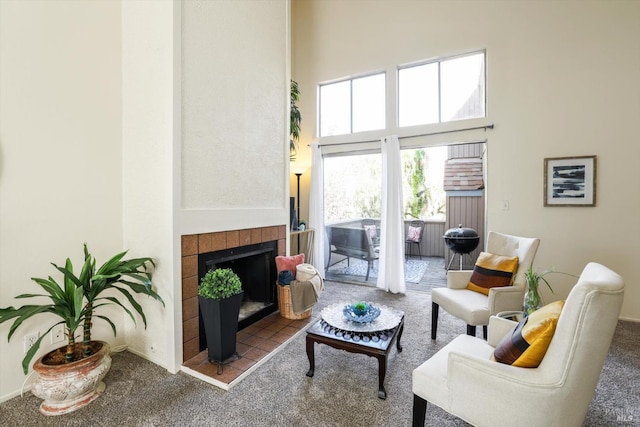 carpeted living room with a high ceiling and a tile fireplace